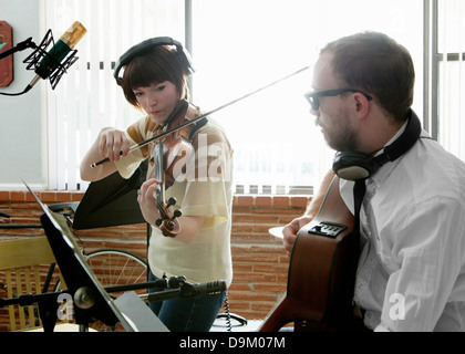 Junger Mann und Frau spielt Geige und Gitarre in der Musik Raum Probe Stockfoto