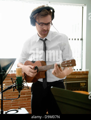 Junge Mann spielt Ukulele in der Musik Raum Probe Stockfoto