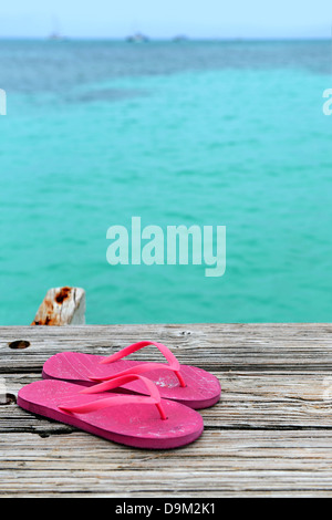Paar rosa Flip flops auf Holzsteg mit Meer im Hintergrund Stockfoto