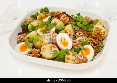 Kartoffelsalat mit Ei und Linsen - warmer Kartoffelsalat mit Ei, Linsen, Petersilie, Speck, Walnüsse, karamellisierten Zwiebeln und Senf. Stockfoto