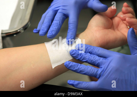 Person, die bereit sind, ein Tattoo am linken Handgelenk, Künstler mit blauen Handschuhen, Künstler mit Schablone Stockfoto