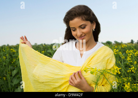Frau stehend in einem Senf Feld lächelnd Stockfoto