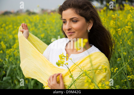 Frau stehend in einem Senf Feld lächelnd Stockfoto
