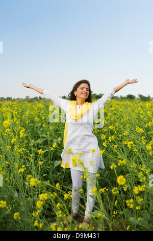 Frau stehend in einem Senf Feld lächelnd Stockfoto