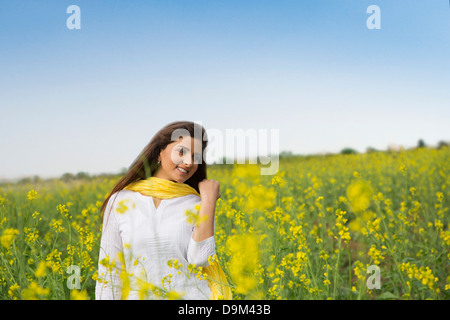 Frau stehend in einem Senf Feld lächelnd Stockfoto