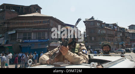 Srinagar, indisch verwalteten Kaschmir 22. Juni 2013. Zivilisten zusehen, wie indische Polizisten neben Wache der verstreuten Melonen in der Nähe der Stelle, wo mutmaßliche militante getötet ihre zwei Kollegen in Srinagar, der Sommer, die Hauptstadt des indischen Kashmir.Security verabreicht, hat in Kaschmir, besonders der Sommer Kapital Stadt von Srinagar, vor Besuch der indische Premierminister Manmohan Singh zu dem umstrittenen Himalaya-Gebiet aufgepeppt worden.  (Sofi Suhail / Alamy Live News) Stockfoto