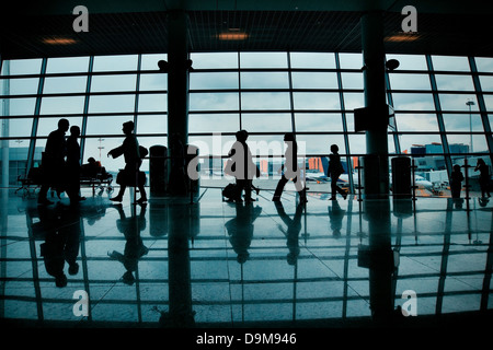 Silhouetten von Personen mit Gepäck zu Fuß am Flughafen Stockfoto