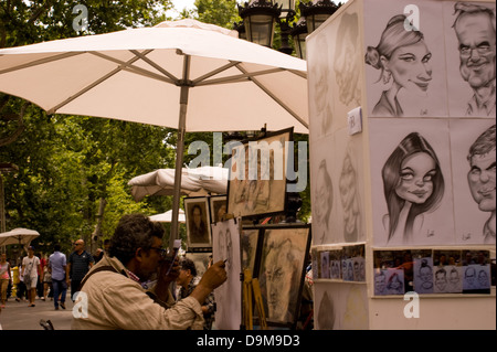 Ein Portrait artist Zeichnung sitzen unter einem Dach arbeiten an Las Ramblas in Barcelona Spanien mit Karikaturen von Menschen auf dem Display Stockfoto