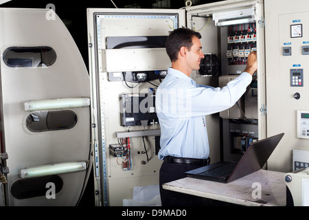 Fachmann reparieren Industriemaschine mit Laptop-computer Stockfoto