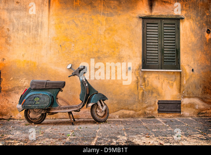 Grün-Vespa-Roller vor verwitterten orange Wand und grünen Fensterläden in Castelbuono, Sizilien Italien Stockfoto