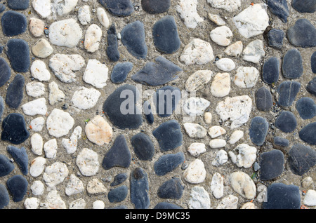 schwarzen und weißen Streifen glatten Kieseln, die inmitten eines konkreten Hintergrund Stockfoto