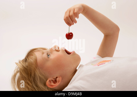 Junges Mädchen zu essen, eine Kirsche. Förderung von gesunder Ernährung bei Jugendlichen Stockfoto