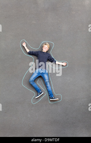 spielerische teenboy auf Boden liegend mit Linien, die um ihn herum Stockfoto