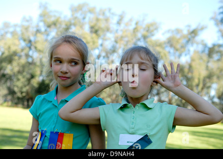 Zwei Schwestern (10 Jahre, 6 Jahre alt) in der Schule sport Karneval, jüngste ziehen lustiges Gesicht zur Kamera. Stockfoto