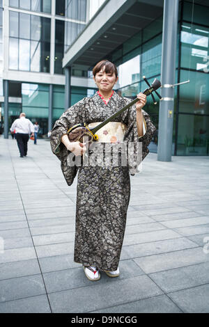 Sanshin - drei stringed traditionelles Musikinstrument aus Okinawa angezeigt wird von einem japanischen Frauen tragen einen Kimono-Bademantel Stockfoto