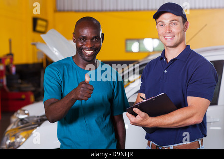 glücklich afrikanischen Kunden aufgeben Daumen in Autowerkstatt Stockfoto