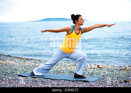Ruhige Szene einer jungen Frau macht eine Pilates posieren am Strand. Stockfoto