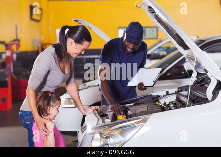 glückliche Mutter und kleine Mädchen in Auto-Service-Center mit Auto-Techniker Stockfoto