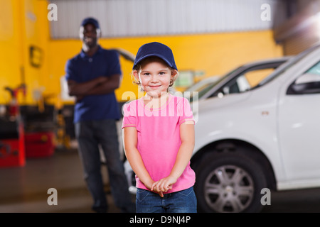 lustige kleine Mädchen mit Auto-Techniker Mütze in garage Stockfoto