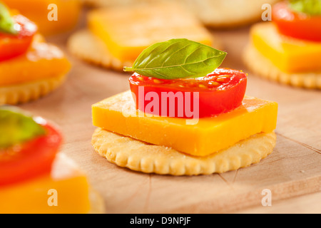 Chedder Käse und Cracker Vorspeise mit Tomaten und Basilikum Stockfoto