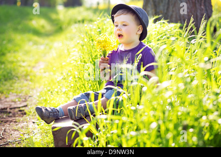 Niedliche kleine Mann sitzen auf den riesigen Koffer Stockfoto