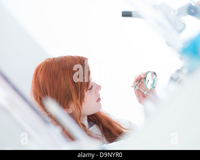 Nahaufnahme von einer Studentin, die unter einer Lupe in einem Chemielabor analysieren Stockfoto