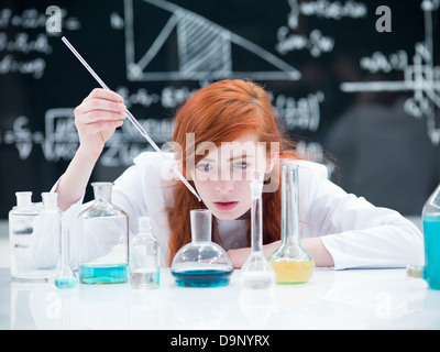 allgemeine Ansicht von einer Studentin, die Durchführung von einem Labor-Experiment auf einem Labortisch mit bunten Flüssigkeiten und Labor-Instrumente mit einem blac Stockfoto