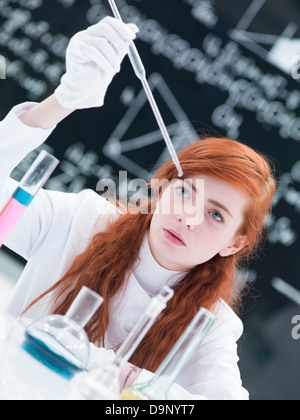 Nahaufnahme von einer Studentin, die Durchführung von einem Labor-Experiment auf einem Labortisch mit bunten Flüssigkeiten und Lab-Tools mit einer blackboa Stockfoto