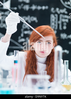Nahaufnahme von einer Studentin, die Durchführung von einem Labor-Experiment auf einem Labortisch mit bunten Flüssigkeiten und Lab-Tools mit einer blackboa Stockfoto