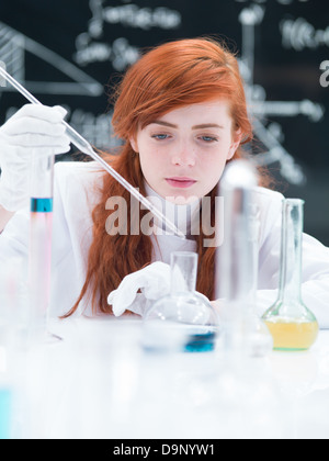 Nahaufnahme von einer Studentin, die Durchführung von einem Labor-Experiment auf einem Labortisch mit bunten Flüssigkeiten und Lab-Tools mit einer blackboa Stockfoto