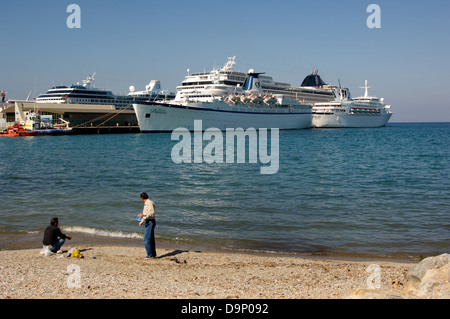 Kreuzfahrtschiffe im Hafen von Kusadasi, Türkei. Zwei Männer am Strand im Vordergrund. Stockfoto