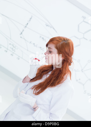 Seitenansicht einer hübschen Studentin in einem Chemielabor riechen, bunte Stoffe und ein White-Board auf dem Hintergrund Stockfoto