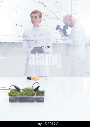 allgemeine Ansicht eines Schülers in einem Chemielabor analysieren Grafik und ihre Lehrerin unter Mikroskop im Hintergrund der Analyse Stockfoto