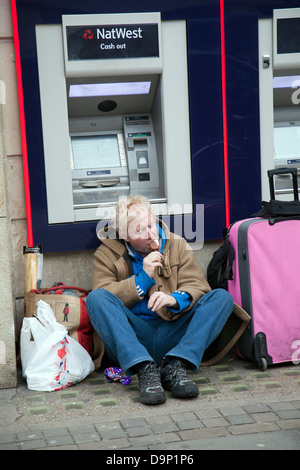 Obdachloser mit hab und gut essen Eis vor Natwest Geldautomaten in London City - UK Stockfoto