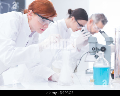 Nahaufnahme von drei Personen in einem Chemielabor chemische Experimente auf einem Labortisch mit Lab Tools und bunte Flüssigkeiten Stockfoto