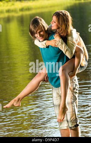 Lachende Mädchen Huckepack reiten seinen Freund im Wasser Stockfoto