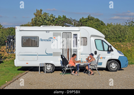 Ein paar Essen in der Sonne, die außerhalb ihrer Reisemobil an der Aire (Zwischenstopp) in Saint-Valery-sur-Somme, an der Nordküste von Frankreich, Europa. Stockfoto