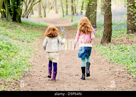 Zwei kleine Mädchen zu Fuß durch Bluebell Wald. Stockfoto