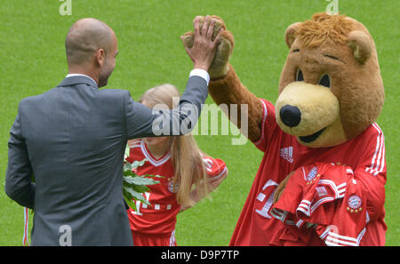 Neue FC Bayern Trainer Josep "Pep" Guardiola gibt Maskottchen Berie ein High-Five während seiner offiziellen Präsentation als Trainer der Bundesliga-Fußball-Club in der Allianz Arena in München, Deutschland, 24. Juni 2013. Foto: PETER KNEFFEL Stockfoto