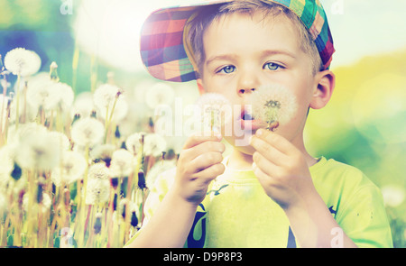 Süßes Kind starrte auf Löwenzahn Stockfoto