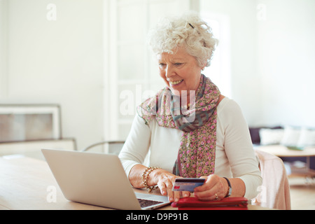 Glückliche alte Dame einige Einkaufen online mit ihrem Laptop zu tun Stockfoto