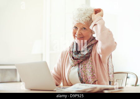 Fröhliche Großmutter zu Hause sitzen verwenden ihr laptop Stockfoto