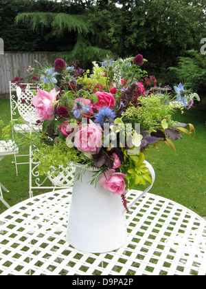 Eine Auswahl von wilden Blumen in einer einfachen weißen Vase in einem englischen Garten. Stockfoto