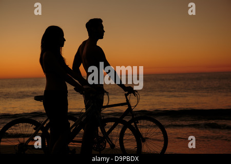 Silhouetten von paar Radfahren zusammen am Strand Stockfoto