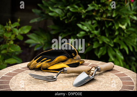 Hand-Gabel und Kelle, mit Handschuhen auf einem Gartentisch. Stockfoto