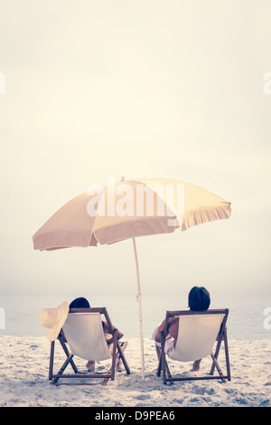 Menschen auf dem Strand liegend auf Liegestühlen entspannen Stockfoto