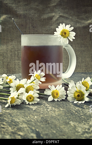 Tasse Tee und Kamille-Blüten auf einem Holztisch. Geringe Schärfentiefe. Stockfoto