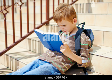 Kleiner Junge liest Buch über Schule Treppen Stockfoto