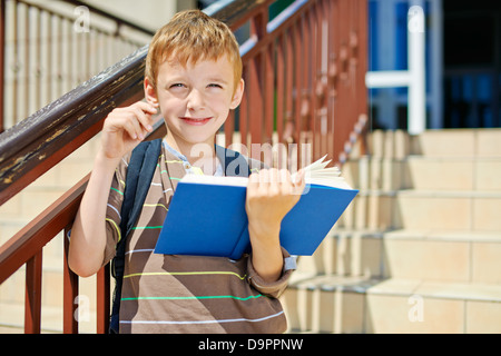 Nachdenkliche junge mit Buch auf Schule Treppe Stockfoto