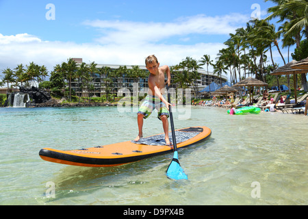 Boy am Paddel Board im Resort in Hawaii, USA Stockfoto